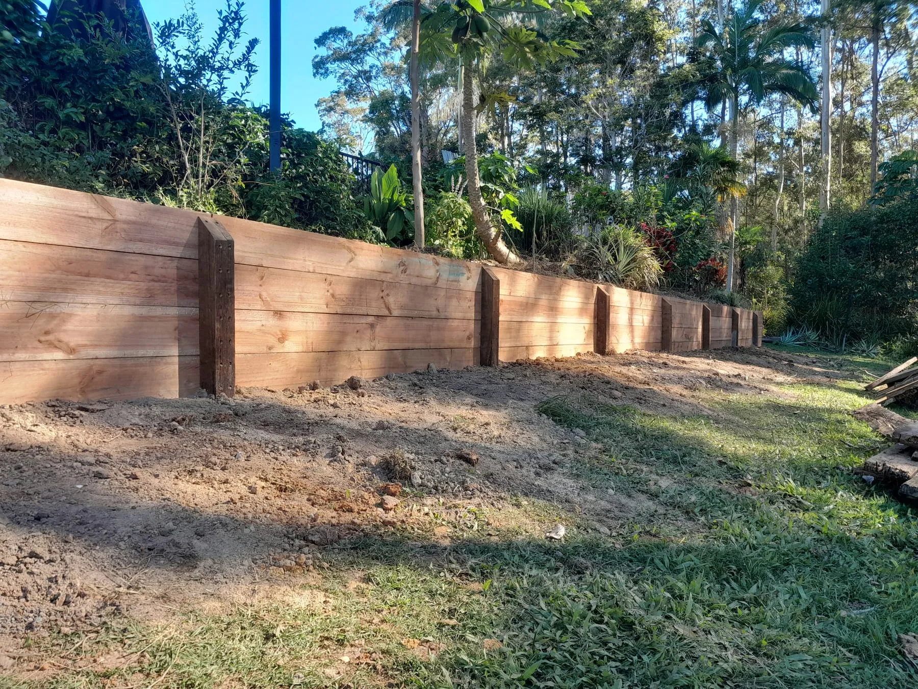 The timber retaining wall from the side, with the ground levelled in front